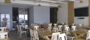 a dining room with tables and chairs and a flat screen tv at Anxhelos Hotel in Himare