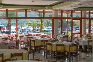 a dining room with tables and chairs and windows at Verdelis Inn in Ancient Epidauros