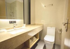 een badkamer met een wastafel, een toilet en een spiegel bij City Comfort Inn Luchuan Hot Spring Plaza High-speed Railway Station 