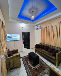 un salon avec canapés et plafond bleu dans l'établissement Enugu Airbnb / shortlet Serviced Apartment, à Enugu
