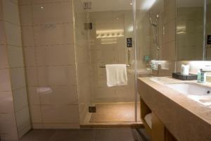 a bathroom with a shower with a sink and a tub at City Comfort Inn Shenyang Olympic Sports Center Wanda Plaza in Shenyang