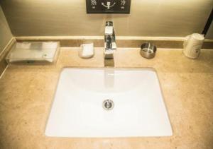 a white sink in a bathroom with a counter at City Comfort Inn Wuzhou Municipal Government Vocational College in Wuzhou