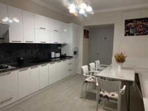 una cucina con mobili bianchi, tavolo e sedie di Cultural Crossing Hotel a Tbilisi City