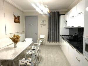 una cucina bianca con tavolo e sedie bianche di Cultural Crossing Hotel a Tbilisi City