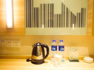 a tea kettle on a kitchen counter with bottles of water at City Comfort Inn Huangshi Daye Tongluowan Business Street in Daye