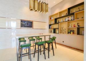 uma cozinha com um bar com bancos verdes em City Comfort Inn Suizhou Railway Station em Suizhou