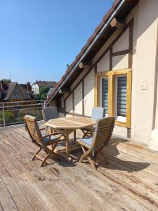 einen Holztisch und Stühle auf einer Holzterrasse in der Unterkunft Appartement-terrasse parking privé Meublé de Tourisme 4 étoiles in Belfort