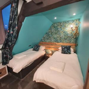 twee bedden in een kamer met een blauwe muur bij Sailaway - Charming Cowes Cottage in Cowes