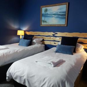 twee bedden in een kamer met blauwe muren bij Sailaway - Charming Cowes Cottage in Cowes