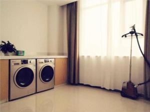 a laundry room with a washer and dryer next to a window at City Comfort Inn Luoyang Lijingmen Metro Station in Luoyang