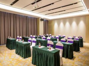 una sala de conferencias con mesas verdes y sillas moradas en Echarm Hotel Huangshi Yingbin Avenue en Huangshi