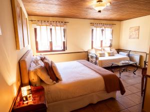 a bedroom with a bed and a table and two windows at Posada el Campanario in Rascafría