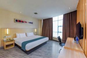 a hotel room with a large bed and a television at City Comfort Inn Ganzhou Railway Station in Ganzhou