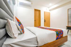 ein Schlafzimmer mit einem weißen Bett mit einer bunten Decke in der Unterkunft FabHotel Amantra in Ahmedabad