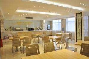 um restaurante com mesas e cadeiras e um balcão em City Comfort Inn Huanggang Huangmei Passenger Station em Huangmei