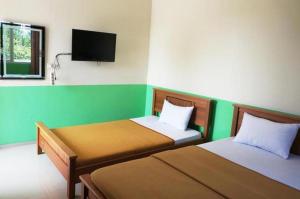um quarto com 2 camas e uma televisão de ecrã plano em Hotel Meigah em Tanjung Pandan
