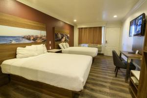 a hotel room with two beds and a desk at Rodeway Inn Carlsbad in Carlsbad