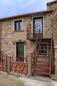 un edificio in pietra con scala e balcone di O LAR DE ROMARÍS I - O LAR DE ROMARÍS II a Padrón