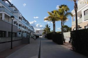 um passeio vazio com palmeiras e edifícios em M515 Apartamento Las Dunas Oliva Nova em Oliva