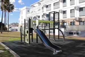 um parque infantil com um escorrega em frente a um edifício em M515 Apartamento Las Dunas Oliva Nova em Oliva