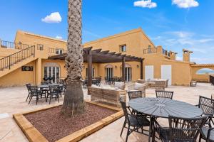 Un patio con mesas y sillas y una palmera. en Beautiful finca with private pool near Jumilla, en La Zarza