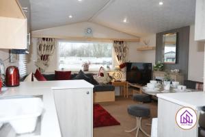 a kitchen and living room with a couch and a table at Bumble Bee Lodge, Hoburne Cotswold Holiday Park in South Cerney