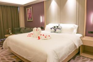 a large white bed with two stuffed animals on it at Lavande Hotels· Yueyang Linxiang Zhongfa in Linxiang