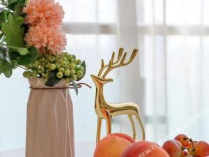 a vase with flowers and a chair next to a vase with fruit at Magnotel Tongxiang Shimao Center in Tongxiang