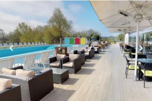 a row of chairs and tables next to a swimming pool at Bumble Bee Lodge, Hoburne Cotswold Holiday Park in South Cerney