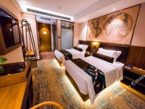 um quarto de hotel com três camas e uma televisão em James Joyce Coffetel Changchun People's Square em Changchun