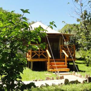 a cabin with a porch and stairs in the grass at Ol Moran Tented Camp in Ololaimutiek