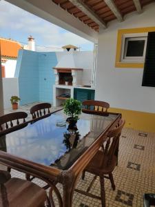a patio with a glass table and chairs and a stove at Lodge & Hike Almograve in Almograve