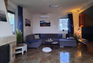 a living room with a blue couch and a tv at Villa Prima Wellness Badacsony in Badacsonytomaj