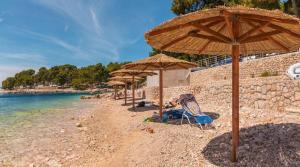 a beach with umbrellas and a person sitting in a chair on the beach at Easyatent Camping Cikat in Mali Lošinj