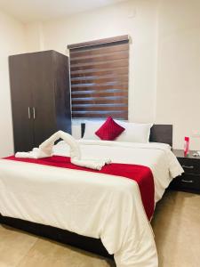 a bedroom with a large white bed with red pillows at Raaha Residency in Kozhikode