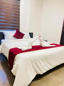 a bedroom with two beds with red and white sheets at Raaha Residency in Kozhikode