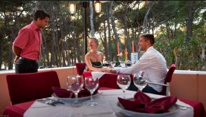 a man serving a woman at a table in a restaurant at Easyatent Camping Cikat in Mali Lošinj