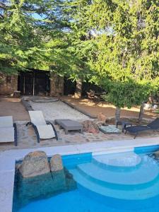 einen Pool mit Stühlen, einem Tisch und einer Feuerstelle in der Unterkunft villa pedriza I in Mataelpino