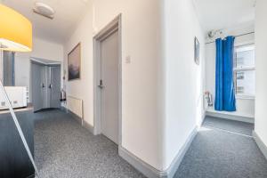 倫敦的住宿－Ryam Suites，走廊上设有白色的墙壁和蓝色的窗帘