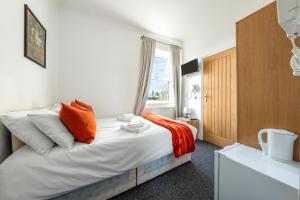 a bedroom with a large bed with an orange pillow at Ryam Suites in London