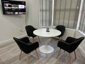 uma mesa branca e cadeiras num quarto com uma televisão em F3, Luxury Flat close to Ilford. sel em Ilford