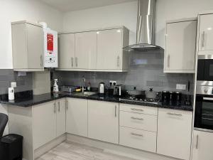 a kitchen with white cabinets and black counter tops at F3, Luxury Flat close to Ilford. sel in Ilford