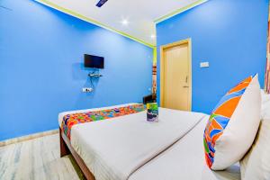 a blue room with two beds and a tv at FabExpress Nest in Kolkata