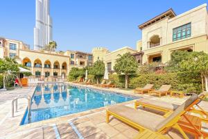 una piscina con sillas y un edificio en Burj khalifa view 1BR Souk al Bahar Tajer Residences Mint avenue Downtown Golden Homes en Dubái