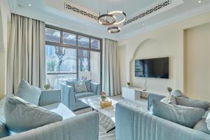 sala de estar con sillas azules y TV en Burj khalifa view 1BR Souk al Bahar Tajer Residences Mint avenue Downtown Golden Homes en Dubái