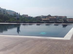 a man standing next to a large swimming pool at Premium apartment with private Parking, Pool with Adriatic view in Tivat
