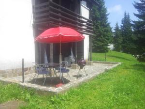 a table and chairs with a red umbrella in front of a building at Apartma Gaber 110 in Zreče