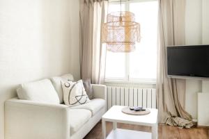 Una sala de estar con un sofá blanco y un televisor. en A cosy studio apartment in the heart of Tallinn, en Tallin 1 foto más