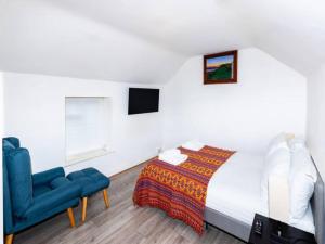 een slaapkamer met een bed en een blauwe stoel bij Pass the Keys Cosy Haven In Glastonbury: One Bedroom Apartment in Glastonbury
