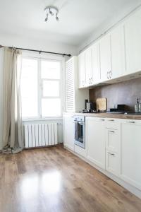 cocina con armarios blancos y suelo de madera en A cosy studio apartment in the heart of Tallinn, en Tallin